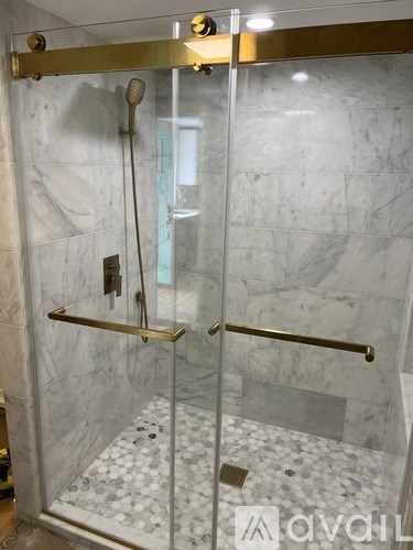 A bathroom with a marble wall and a glass shower door.