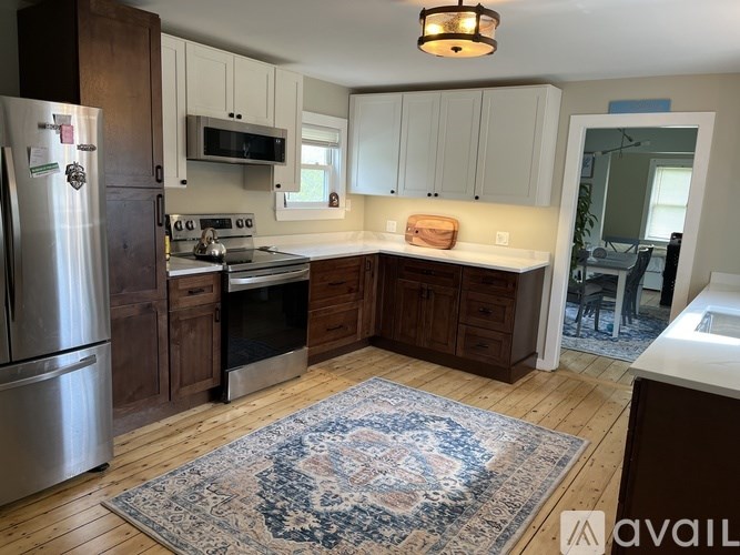 A kitchen with a rug on the floor and a refrigerator on the left.