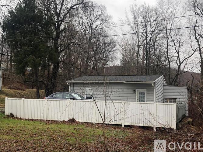 A house with a white fence and a car parked in front.