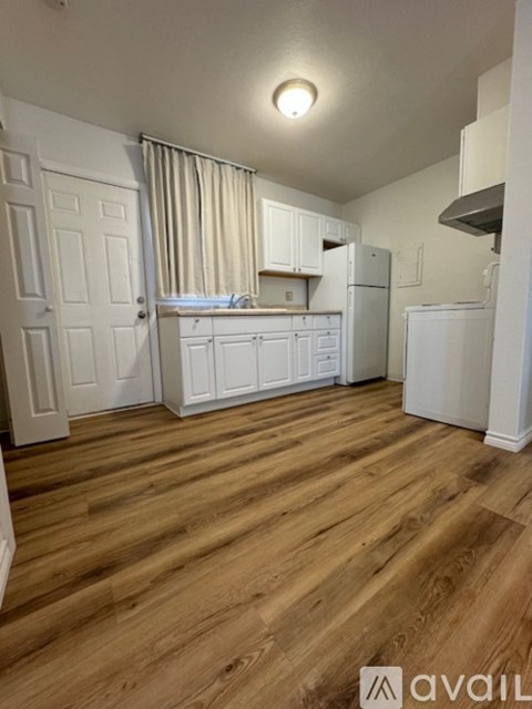 A kitchen with white cabinets and a wooden floor.