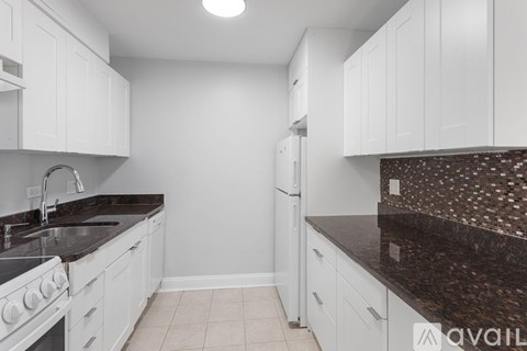 A kitchen with white cabinets and a black countertop.