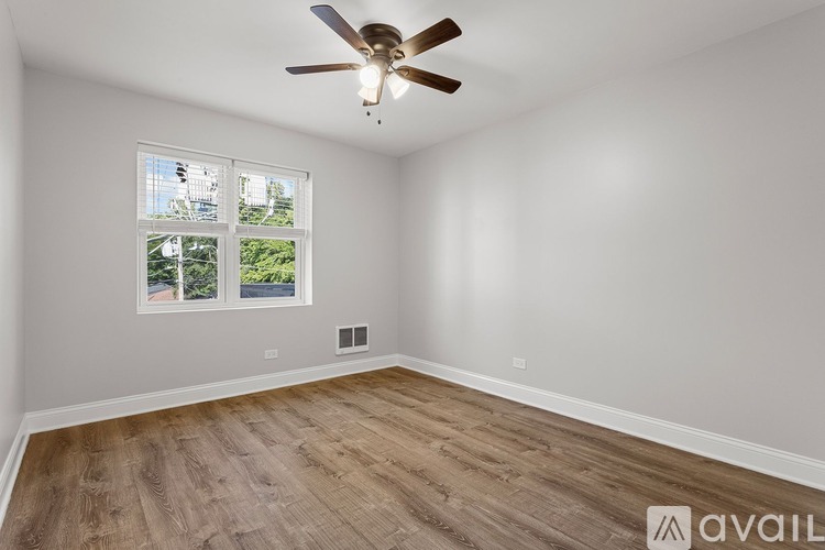 A room with a ceiling fan and a window showing a view of trees.
