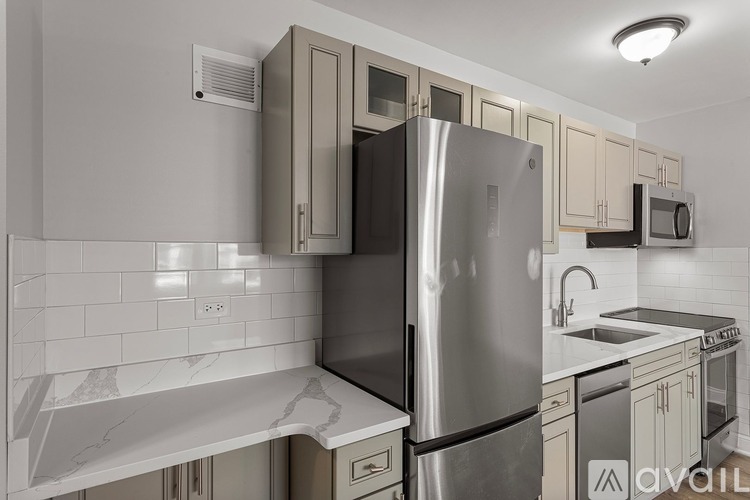 A modern kitchen with a stainless steel refrigerator and a marble countertop.