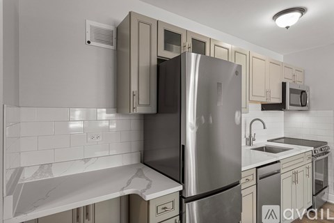 A modern kitchen with a stainless steel refrigerator and a marble countertop.