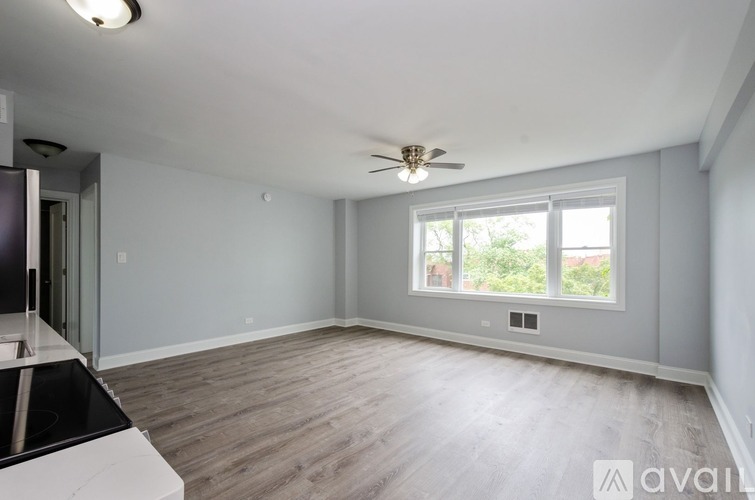 A spacious room with a ceiling fan and a window overlooking a green area.