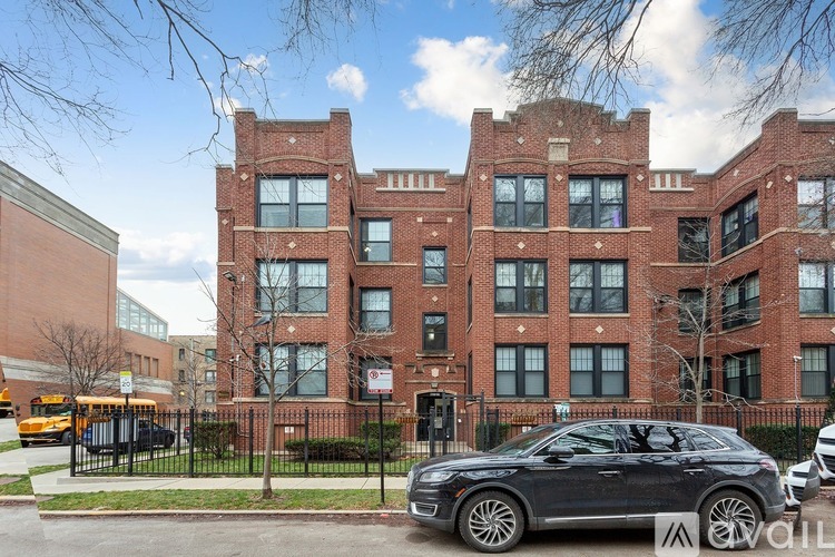 A black car is parked in front of a red brick building.