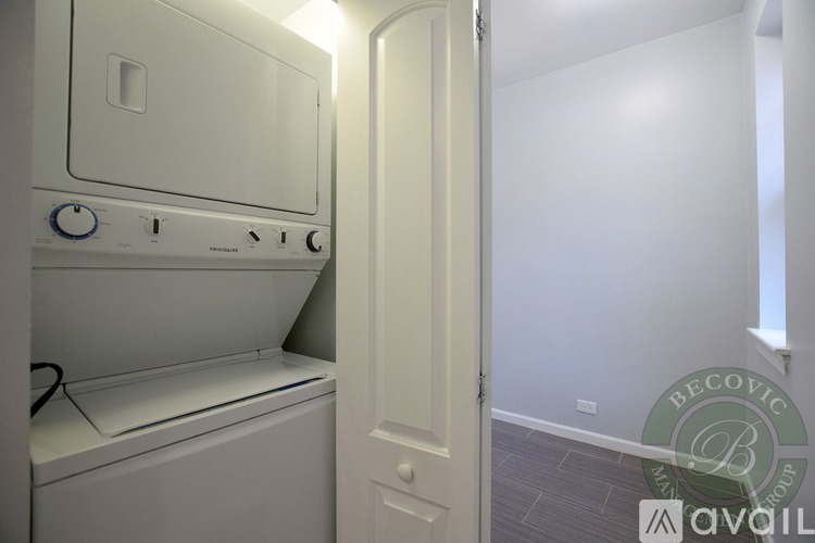 A white washing machine is in a small room with a door.