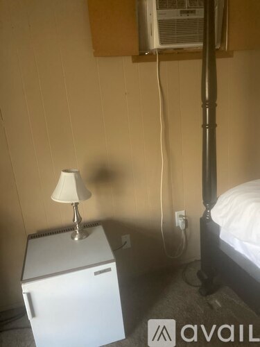 A lamp on a table next to a bed in a room.