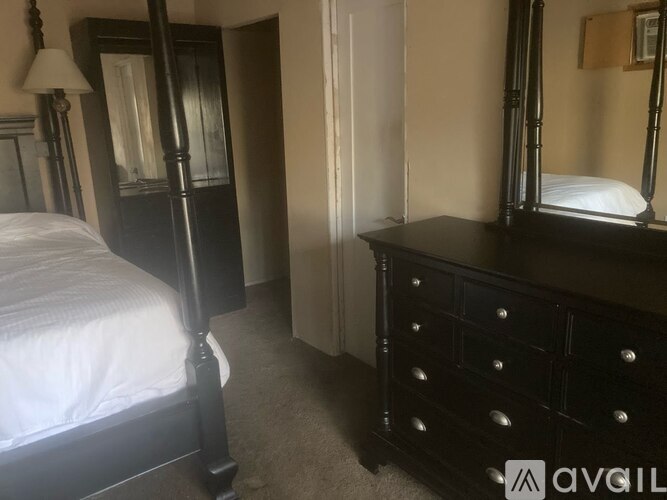 A bedroom with a bed, dresser, and mirror.
