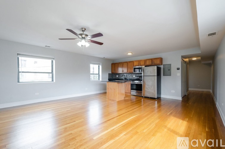 A spacious kitchen with wooden floors and a ceiling fan.
