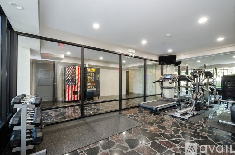 A gym with a row of dumbbells on the left and a row of treadmills on the right.