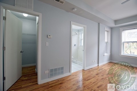A room with wooden floors and white walls, with a window on the right side.