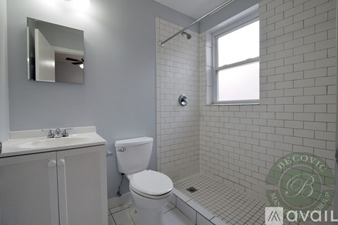 A white toilet sits in a bathroom with a white sink and a mirror.