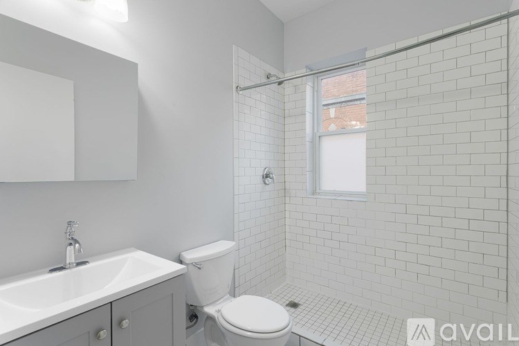A white bathroom with a toilet, sink, and tiled walls.