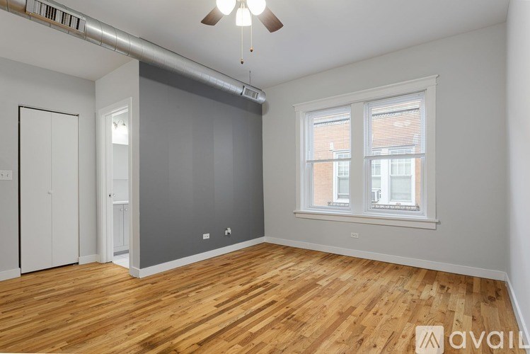 A room with wooden floors and a window with blinds.