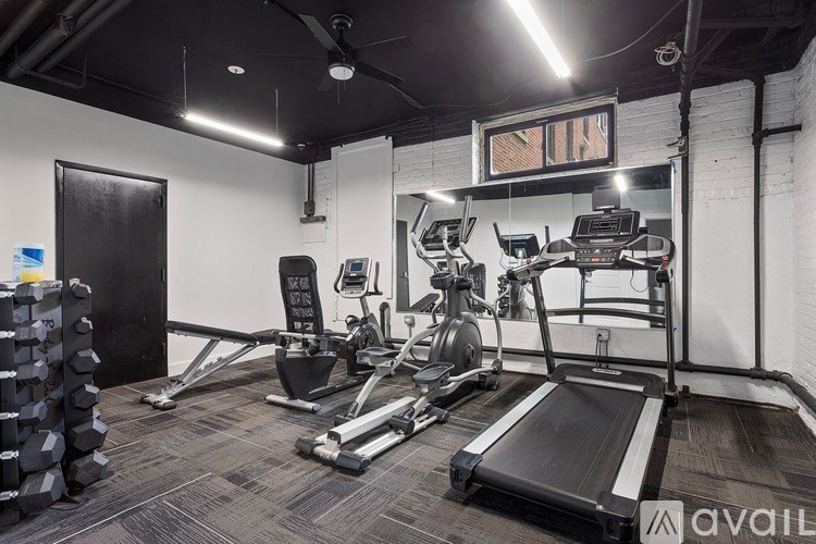 A gym with a variety of equipment including treadmills, weights, and exercise machines.