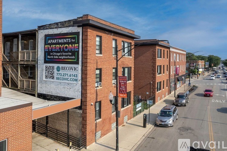 A large billboard for apartments is on the side of a brick building.