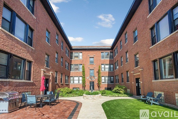 A courtyard surrounded by red brick buildings with a table and chairs in the middle.