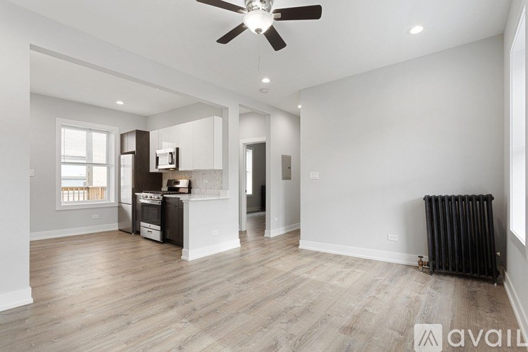 A spacious living room with a kitchen area in the background.