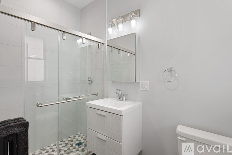A white bathroom vanity with a mirror and a glass shower stall.
