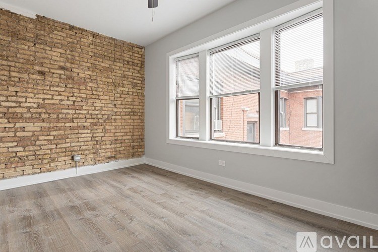 A room with a brick wall and a window overlooking a building.