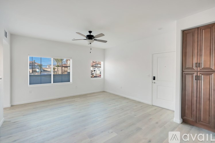 A room with a ceiling fan and a large window with a view of a body of water.