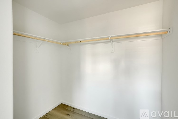 A white wall with a wooden floor and a white shelf.