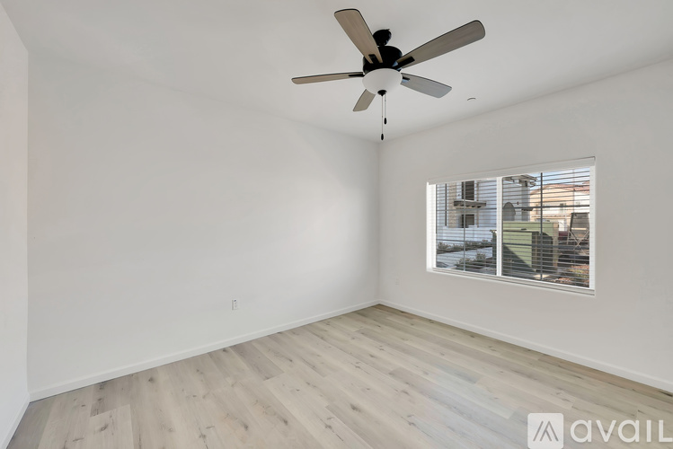 A room with a ceiling fan and a window overlooking a building.