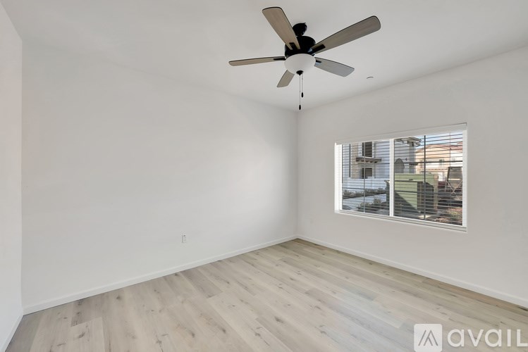 A room with a ceiling fan and a window overlooking a building.
