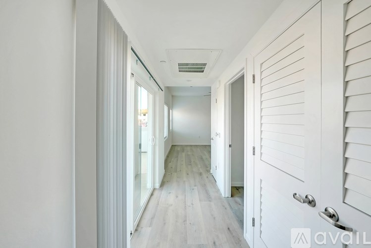 A long white hallway with doors on both sides.