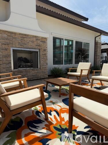 A patio with chairs and a table with a stone wall and window.