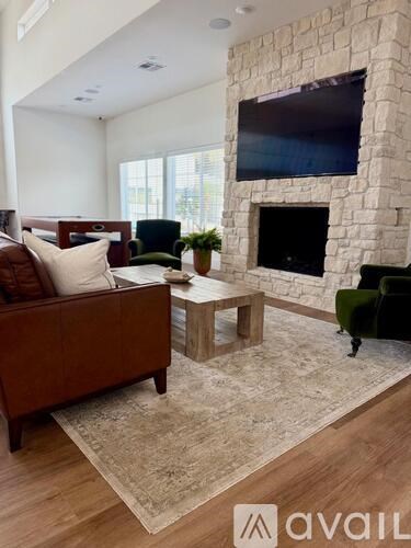 A living room with a stone fireplace and a flat screen TV mounted above it.
