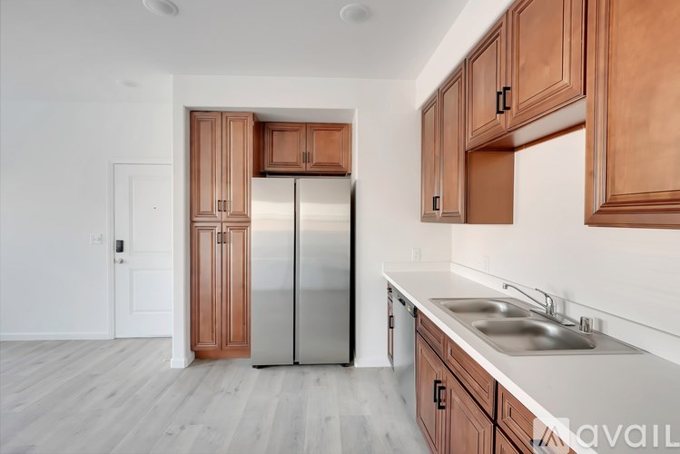 A kitchen with wooden cabinets and a stainless steel refrigerator.