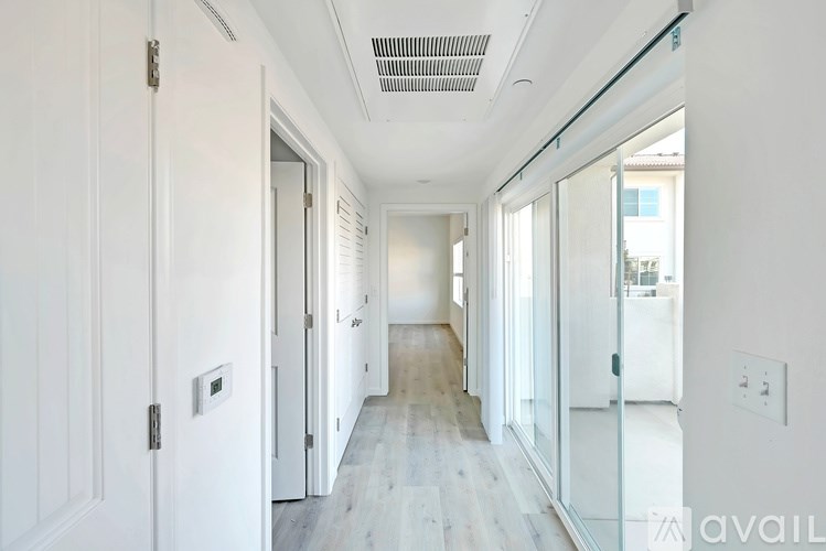 A long hallway with white walls and wood flooring.
