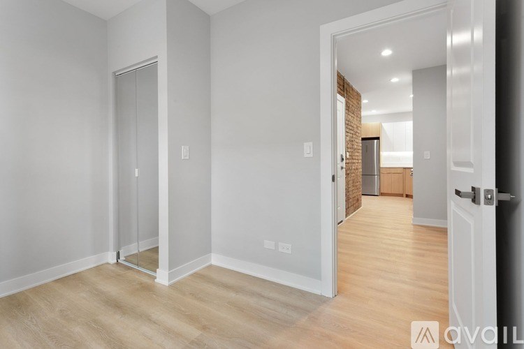 A white hallway with a glass door and a wooden floor.