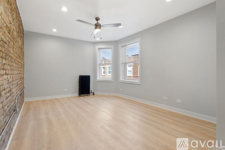 A spacious room with a brick wall on the left and a wooden floor.