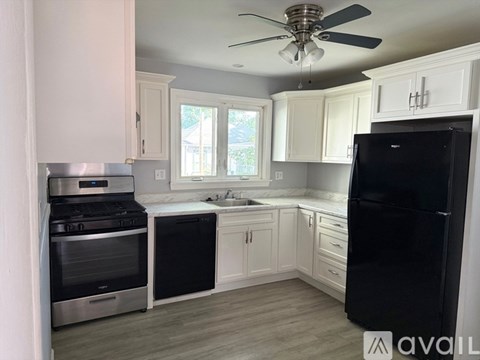 A kitchen with a black fridge, stainless steel oven and white cabinets.