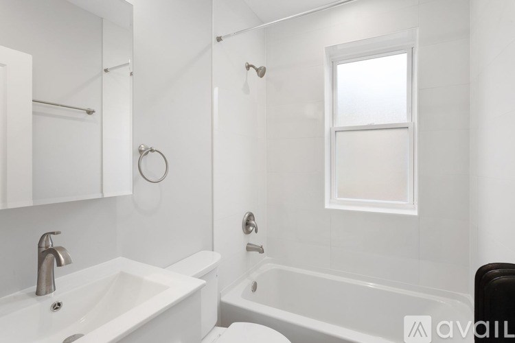 A white bathroom with a sink, mirror, and tub.