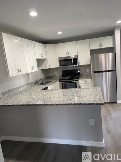 A kitchen with white cabinets and a granite countertop.