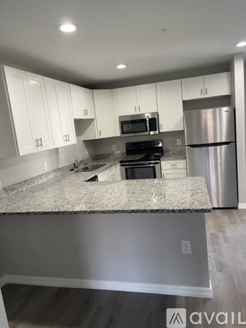 A kitchen with white cabinets and a granite countertop.