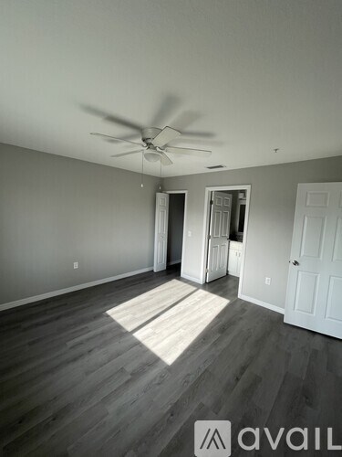 A room with a ceiling fan and wooden flooring.