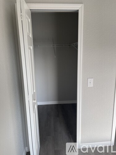 A white closet with a hanger rod and a light switch on the wall.
