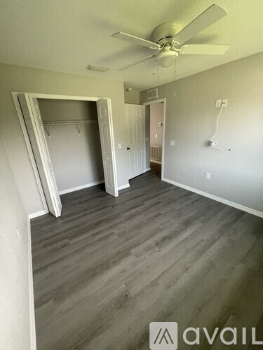 A room with a ceiling fan and a wooden floor.