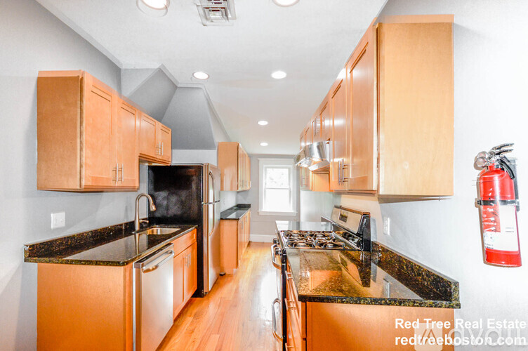 A kitchen with wooden cabinets and black countertops.