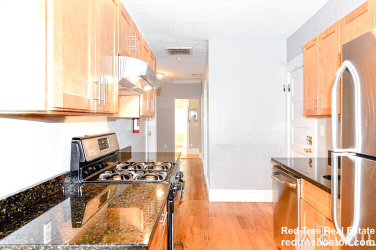 A kitchen with a black counter top and wooden cabinets.
