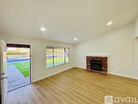 A room with a fireplace and a sliding glass door leading to a backyard.