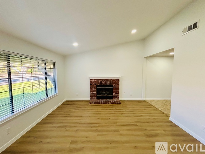 A spacious room with a fireplace and wooden flooring.