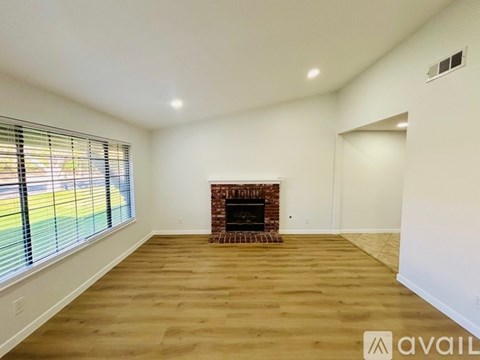 A spacious room with a fireplace and wooden flooring.