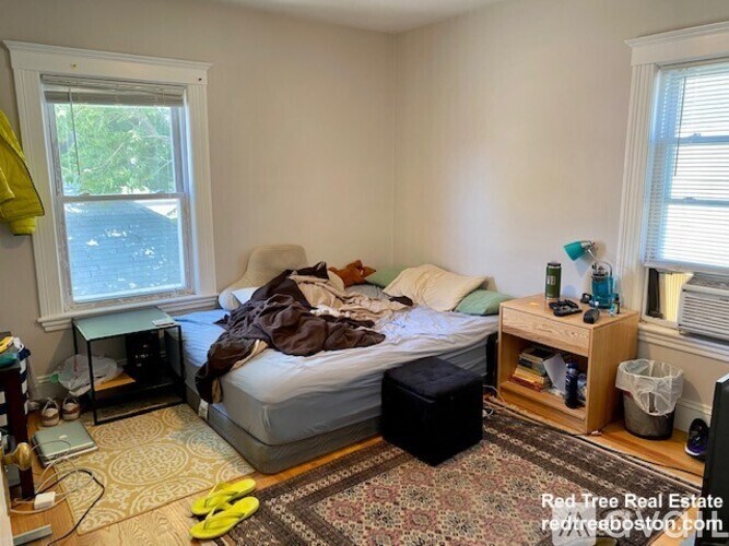 A bedroom with a bed, nightstand, and window.