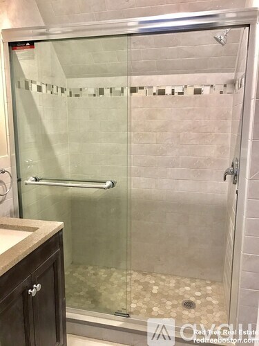 A shower with a glass door and a silver handle.